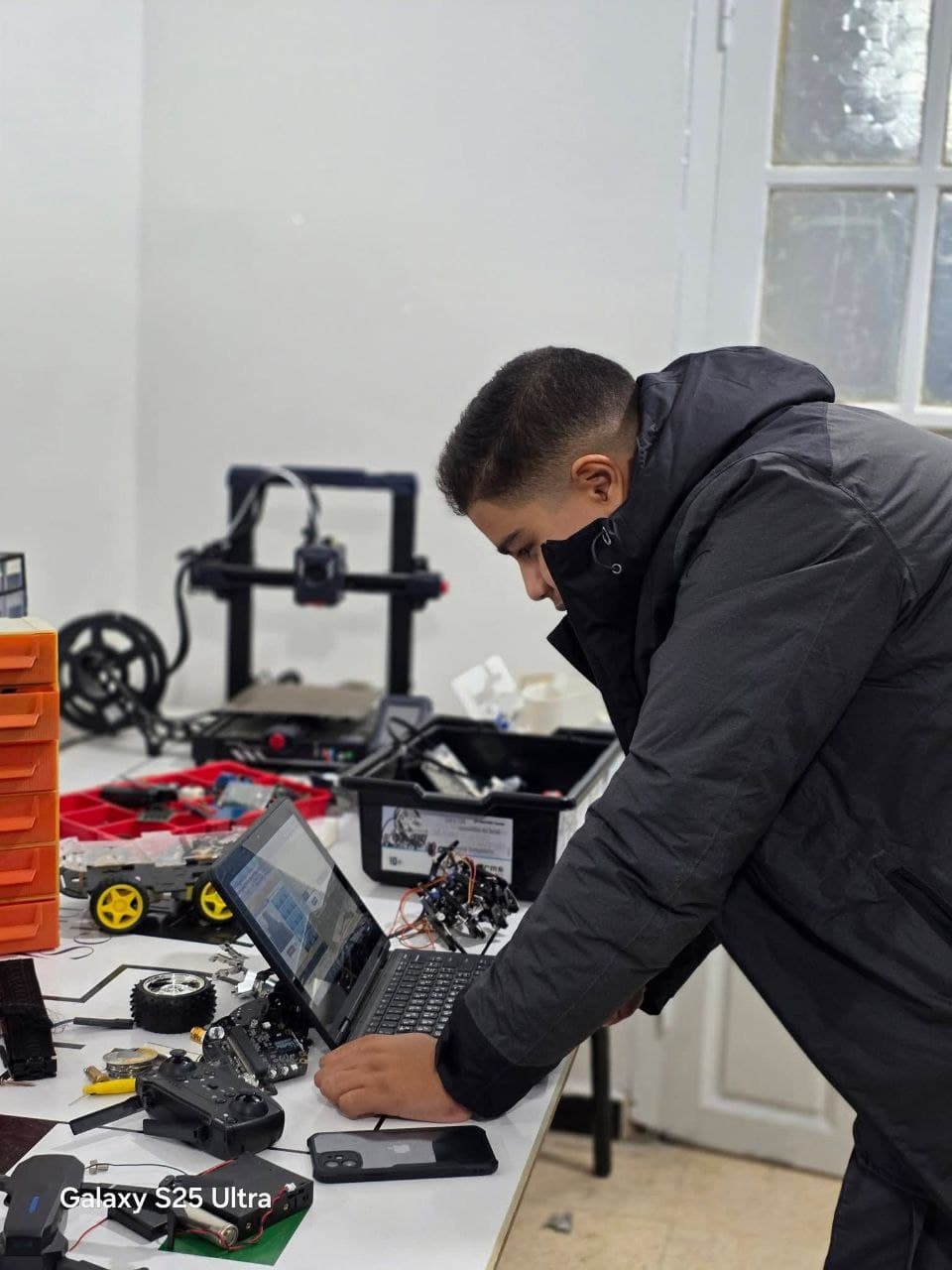 Student working in workshop with laptop and robotics
